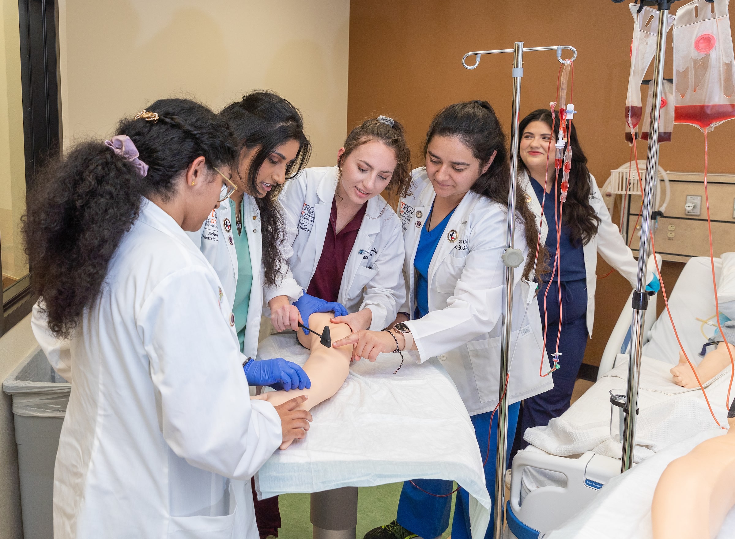 SOPM students in hospital bed assisting patient.